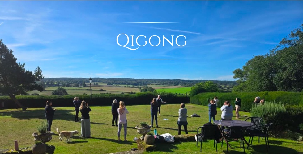 Qigong teacher on the lawn with arms raised enjoying the sunshine